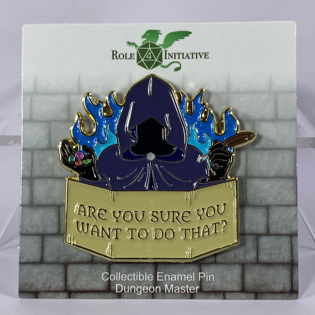 A soft enamel pin depicting a mysterious Dungeon Master in a hooded robe. The dice in the right hand stand for their role as arbiter of fate, the quill for their mastery of storytelling.